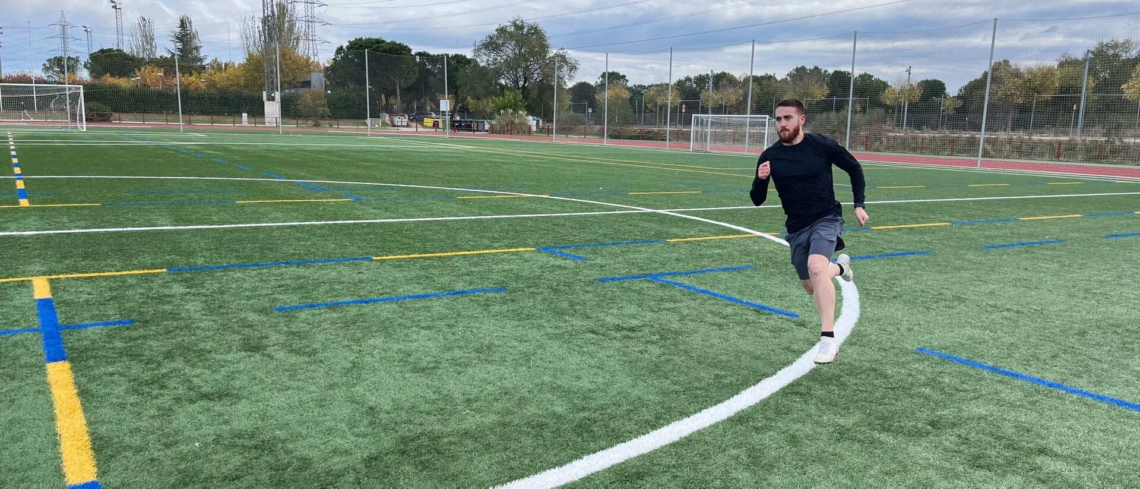 Hombre joven realizando carreras en un campo de fútbol.